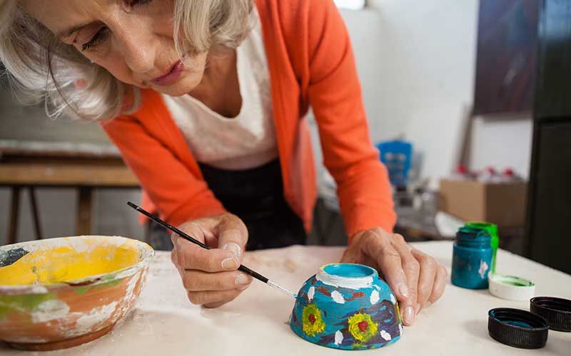 woman painting a ceramic bowl